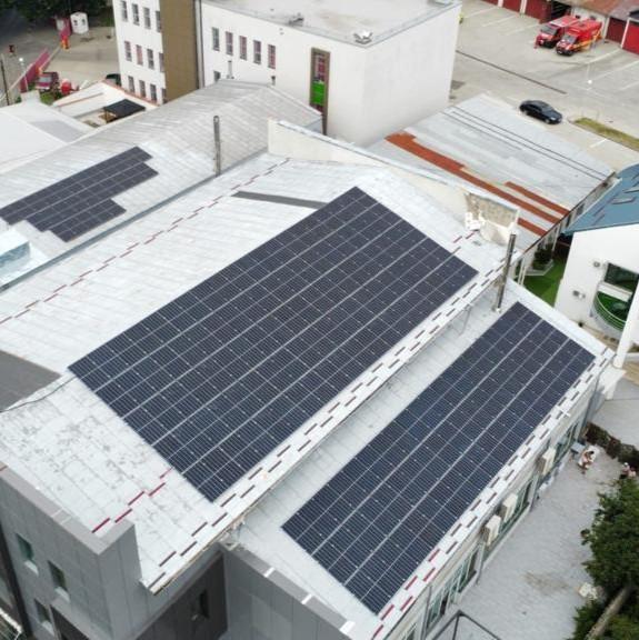 Solar panels mounted on an expansive industrial rooftop.